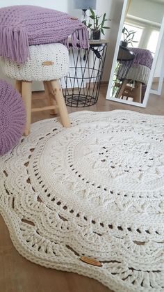 a white crocheted rug on the floor next to a chair