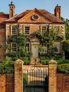 a large brick house with an iron gate and ivy covered trees on either side of it