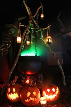 halloween pumpkins lit up in the dark with lights on them and hanging from branches