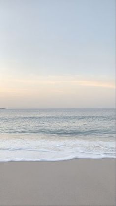 an empty beach with the ocean in the background