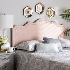 a bed with pink headboard and pillows on top of it next to two nightstands