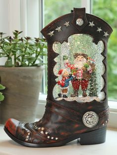 a pair of boots that are sitting on a window sill in front of a potted plant