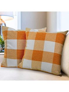 two orange and white pillows sitting on top of a couch