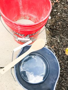 a red bucket and blue bowl sitting on the ground