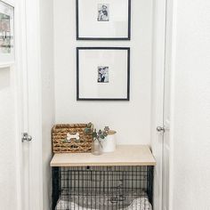 a small dog cage in the corner of a hallway next to a wall with pictures on it