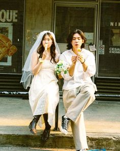 a man and woman sitting on the curb eating food