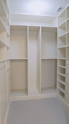 an empty walk in closet with white shelves