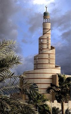 a very tall tower with a clock on it's side next to palm trees