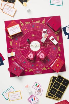 a board game surrounded by cards and magnets on a white surface with other items