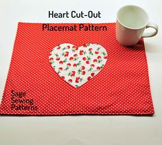 a red placemat with a heart on it next to a white cup and saucer