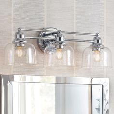 three light bathroom fixture with clear glass shades and chrome finish on the wall above it