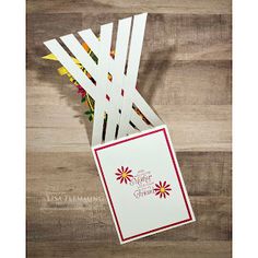 a bunch of white sticks with red and yellow flowers on them sitting next to a greeting card