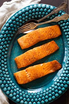 three fish fillets on a blue plate with a fork and spoon next to it