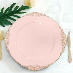 a pink plate sitting on top of a white table next to a green palm leaf