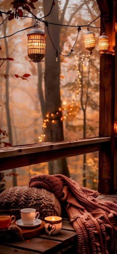 an outdoor deck with lights strung from the ceiling and blankets on it, next to a cup of coffee