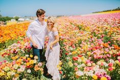 a man and woman standing in a field full of flowers