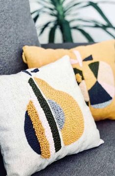 two pillows sitting on top of a gray couch next to a potted green plant