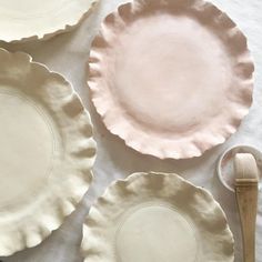 three plates and two spoons sitting on a white table cloth next to each other