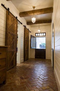 an open door leading into a hallway with brick flooring and wooden shutters on the walls