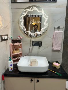 a bathroom with a sink, mirror and other items on the counter in front of it