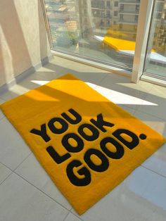 a yellow rug with the words you look good on it in front of a window