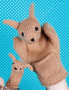 a person holding up a knitted stuffed animal in their left hand and the other hand is wearing a mitten