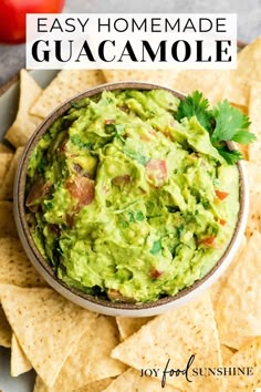 a bowl filled with guacamole surrounded by tortilla chips and tomatoes