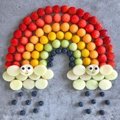 a rainbow made out of fruit with eyes on the side and berries in the middle