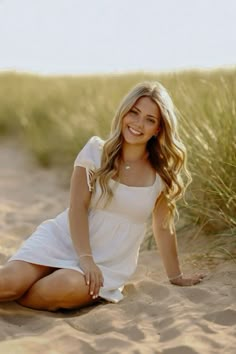 a woman is sitting in the sand with her legs crossed and smiling at the camera