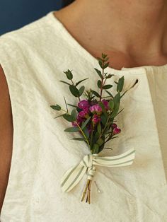 a woman wearing a white dress holding a bouquet of flowers in her hand and tied with a ribbon