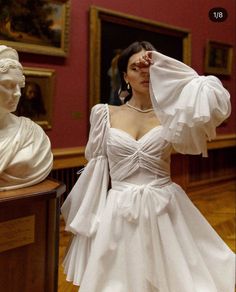 a woman in a white dress standing next to a bustle