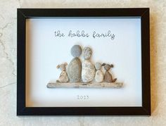 the family is made out of rocks in a shadow box with a black border around it