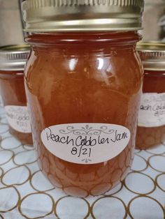 three jars of peach cobbler jam on a table