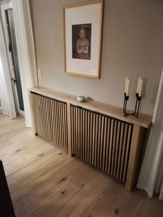 an empty room with wood flooring and a painting on the wall above two radiators