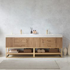 a bathroom vanity with two sinks and towels on the counter next to each other in front of a gray wall