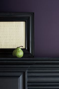 an apple sitting on top of a black mantle next to a framed photo and writing paper