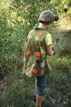 a young boy wearing a green backpack with orange and brown polka dots on the back