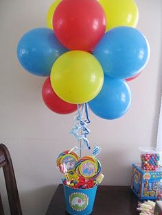 a bunch of balloons that are on top of a table with some candy in it