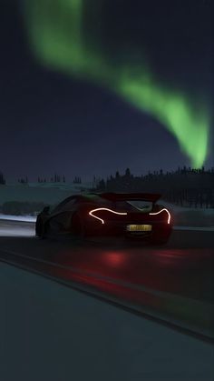 a car driving down the road with an aurora light in the background