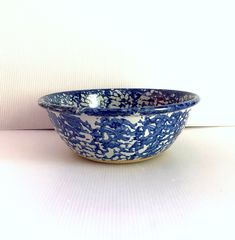 a blue and white bowl sitting on top of a table next to a wall in the background