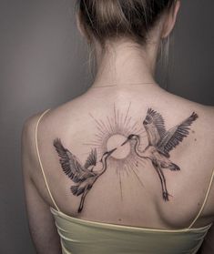 the back of a woman's neck with two birds flying towards eachother