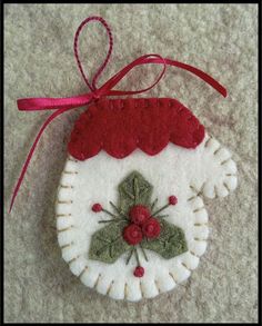 an ornament hanging from a red ribbon on top of a white table cloth