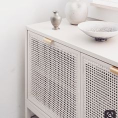 a white sideboard with two vases on top and one bowl sitting on it