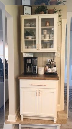 a kitchen with white cabinets and brown counter tops, including a coffee maker on top of the cabinet