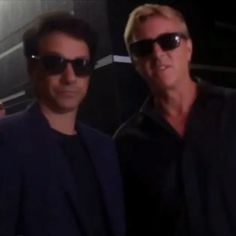 two men standing next to each other wearing sunglasses