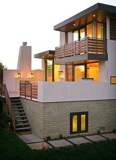 a modern house with stairs leading up to the second floor and two story windows at dusk