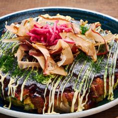 a blue plate topped with food covered in sauce and toppings on top of a wooden table