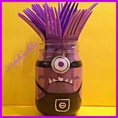 a glass jar with purple hair and eyes painted on the inside, sitting in front of a yellow wall