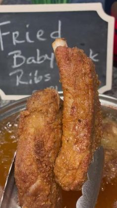 two fried chicken sticks sitting on top of a metal pan filled with gravy