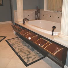 a bath tub sitting next to a white sink in a bathroom with columns on the wall